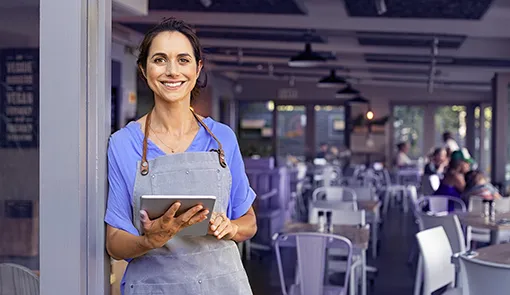 Proget zarządzanie mobilnością dla sieci handlowych, uśmiechnięta kelnerka z tabletem w ręku, w tle restauracja