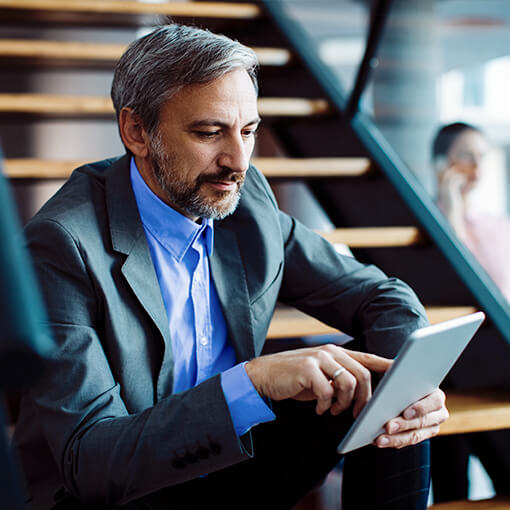Proget mobility management for mobile workers, man with tablet sits on stairs