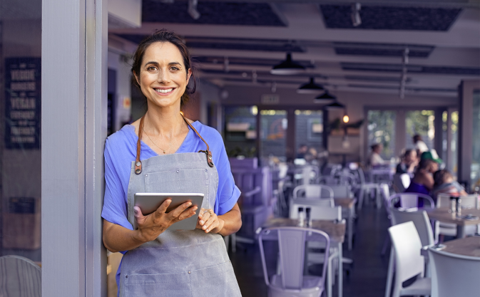 a waitress with a tablet in her hand stands in front of a restaurant