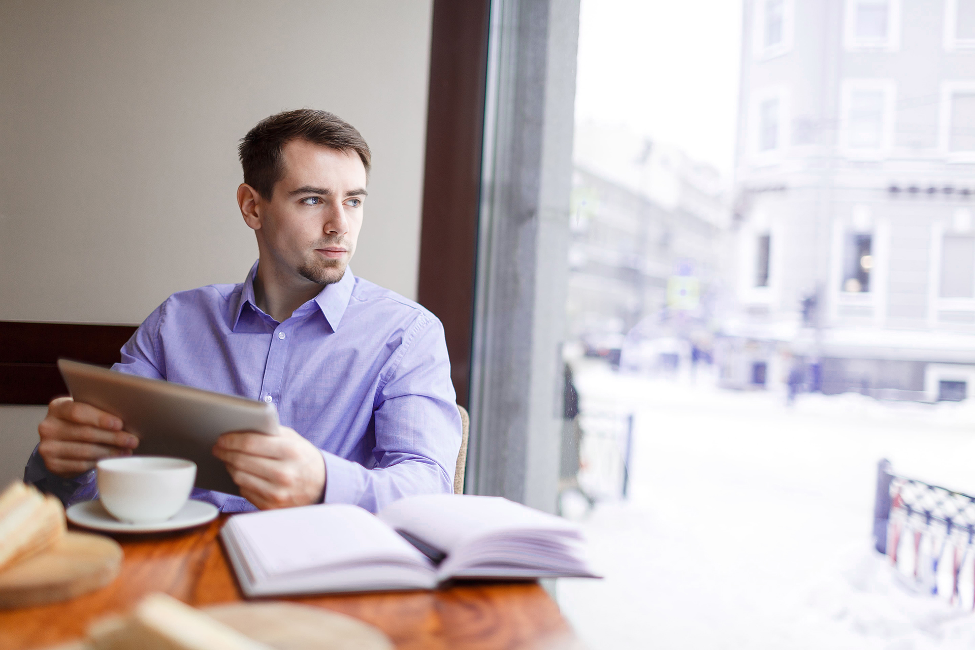 situational awareness, man with tablet in cafe looks out window