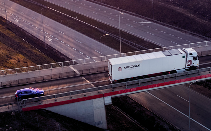a truck with the Kawczyński Logistics logo drives over a flyover