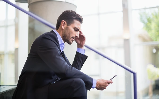 businessman is sitting on the stairs with a phone in his hand
